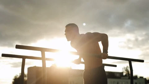 Strong young man doing triceps exercises on parallel bars during street workout Stock Footage 121901659