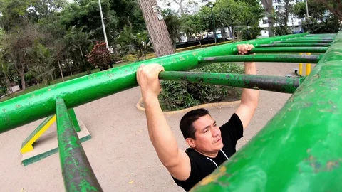 Strong young man is doing triceps dips on parallel bars. Exercising outdoors in 動画素材 125444317