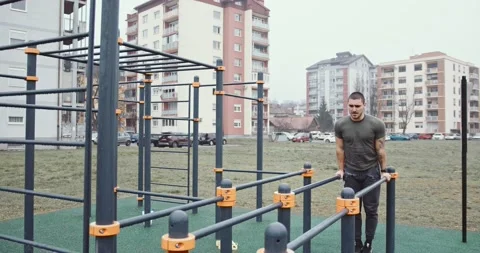Strong young man doing triceps dips on parallel bars at park 動画素材 145347637