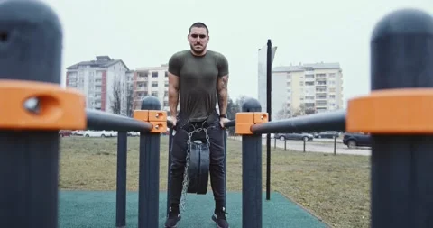 Strong young man doing triceps dips on parallel bars at park Stock Footage 145347700