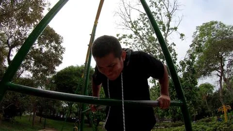 Strong young man is doing triceps dips on parallel bars. Exercising outdoors in Foto stock