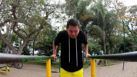 Strong young man is doing triceps dips on parallel bars. Exercising outdoors in Stock Photos