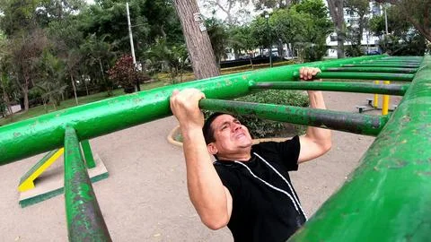 Strong young man is doing triceps dips on parallel bars. Exercising outdoors in Stock Photos