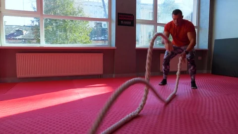 Strong young man exercising arms and shoulders with rope at gym. Bodybuilder Stockbeeldmateriaal 88618493