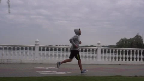 Strong young man jogging along river. Sportive man training on city embankment. Video stock 141075201