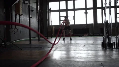 Strong young man training with battle ropes in crossfit gym Stock Footage 131218128
