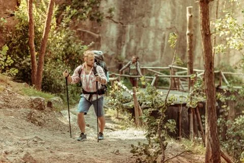 Strong young man using special tourist equipment while hiking in the mountains Foto stock