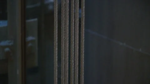 Strongly coiled elevator cables hang suspended in an elevator shaft Stock Footage 99262261