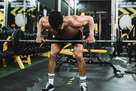 Strongman lifting weights with the barbell in a gym Stock Photos
