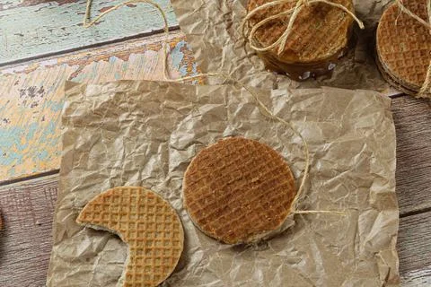 Stroopwafel with a bite on brown paper next to another cookie and sisal strin Stock Photos