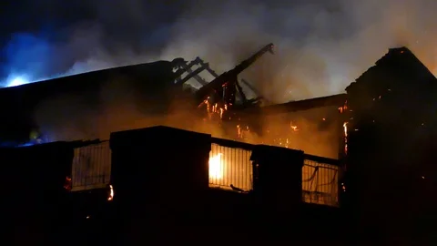 Structural destruction caused by fire atop a condo building during evening Vídeos de archivo 113324728