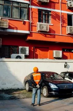 Structural engineer in orange work vests and hard bats looking up building re Stock Photos