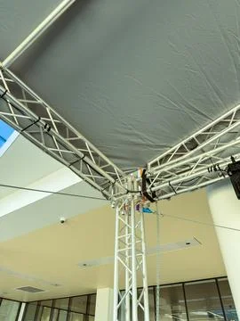 Structure holds up a canopy inside a modern building during an event setup Stock Photos
