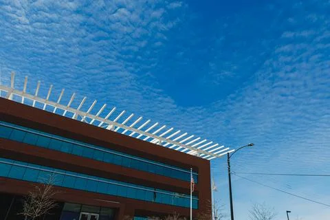 A structure with large glass windows sits beneath a blue sky. The clouds are  写真素材