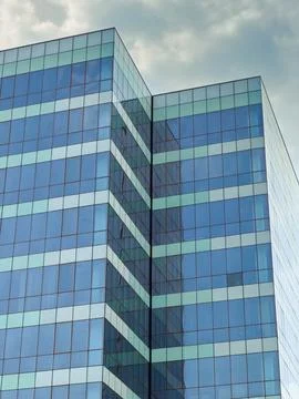 The structure shows multiple floors of glass panels reflecting the sky. The b Stock Photos
