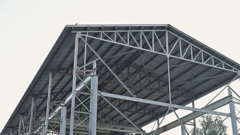 A structure undergoes roof construction using metal beams and panels in an urban Stock Footage 345879134