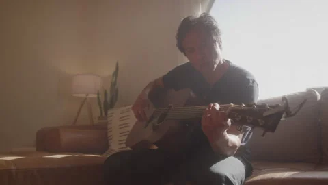 Strumming Guitar Player Sits On Couch Stock Footage 208781881