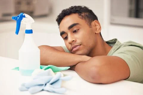 Stuck in a loop of endless cleaning. Shot of a young man looking bored while  Stock Photos
