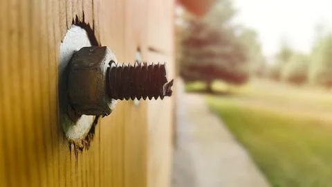 A stud with a nut and washer sticks out of a wooden post of a frame house Stock Photos
