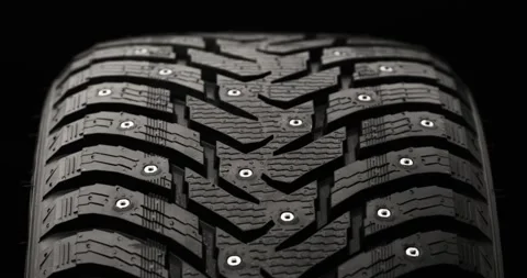 Studded winter tire rotating on black background Stock Footage 320971625