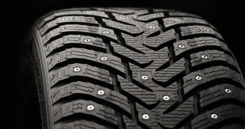 Studded winter tire rotating on black background Stock Footage 320971629