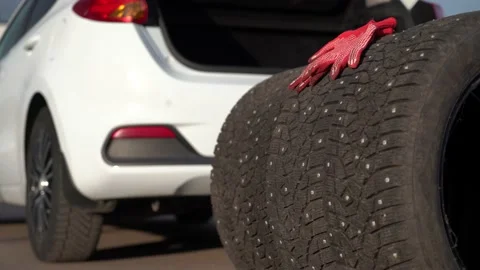 Studded winter tires in front of a opened car trunk Stock Footage 163796084