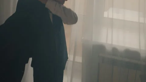 Student adjusting attire. Focused student adjusting clothing in softly lit room Stock Footage 337232282