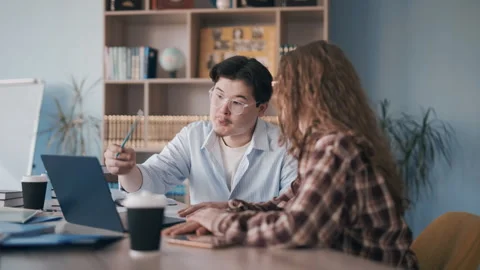 Student and tutor in focused learning session at desk with laptop and books Stock Footage 341337606