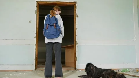 Student with backpack entering abandoned building, stray dog resting outside Video stock 342087757