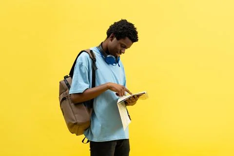 Student With Backpack Reading Map on Yellow Background Stock Photos
