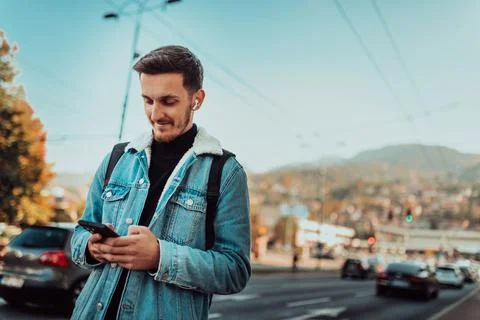 A student with a backpack using a smartphone on the street, checking email Stock Photos