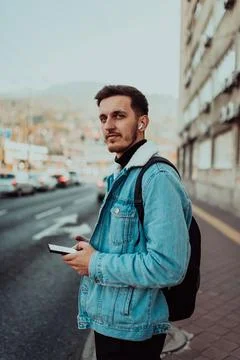 A student with a backpack using a smartphone on the street, checking email Foto stock