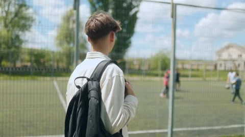 Student with backpack watching activity at the school sports field Stock Footage 310882587