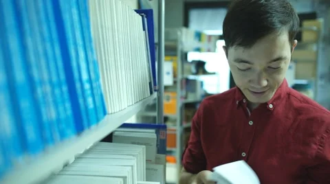 Student boy chooses of a book in the library Stock Footage 68565028