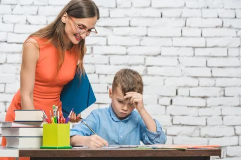 Student boy doing work in school supervised by his teacher Stock Photos