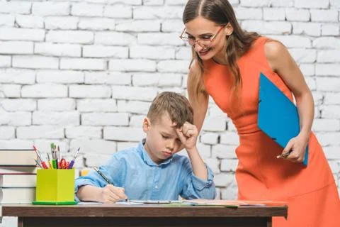 Student boy doing work in school supervised by his teacher Stock Photos