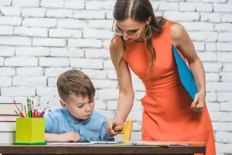 Student boy doing work in school supervised by his teacher Stock Photos