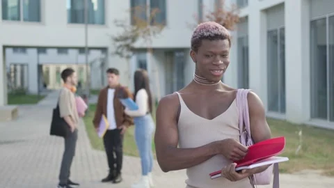 Student boy looking at camera while his friends are behind, in university campus Stock Footage 221559131