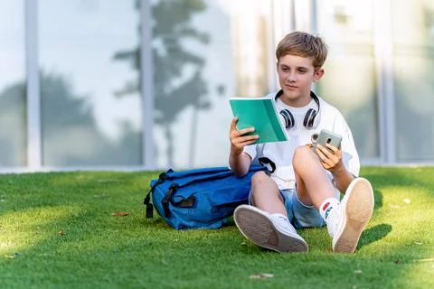 Student boy sitting on the grass with a notebook while relaxing after school. 스톡 사진