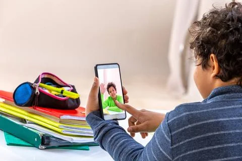 Student boy with smartphone distracting from study. Teen playing game at h... 스톡 사진