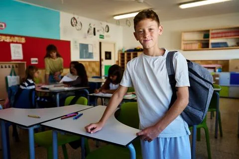 Student boy smiling with backpack in classroom Stock Photos