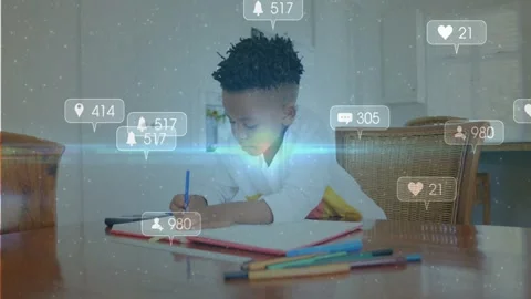 Student boy studying at table writing homework, social icons appearing with blue Stock Footage 330144204