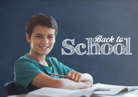 Student boy at table against blue blackboard with back to school text Foto stock