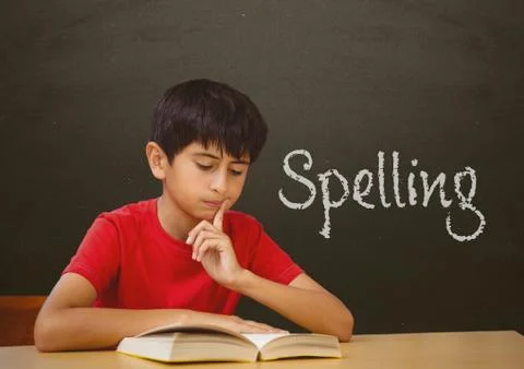 Student boy at table against grey blackboard with spelling text 스톡 사진