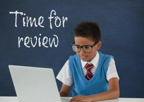 Student boy at table using a computer against blue blackboard with time for Stock Photos