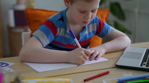 Student boy write note in notebook, make homework task at desk with laptop Stock Footage 154591476