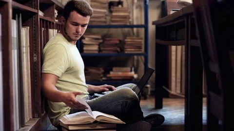 Student browsing a book and using laptop Stock Footage 77794698