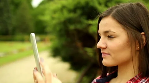 Student browsing interneton the tablet in park Stock Footage 64469526