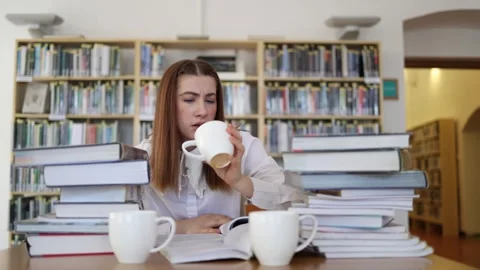 Student checks empty cup after drinking too much coffee while studying Stock Footage 341655543