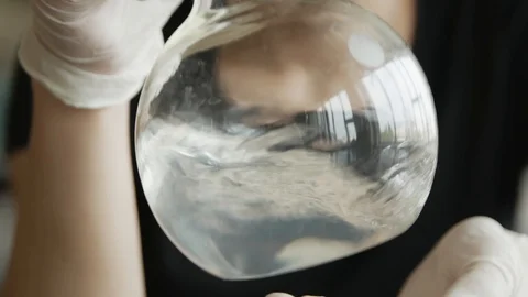 Student chemist pours moves the reagent in the flask in chemistry classroom.  스톡 동영상 113347566